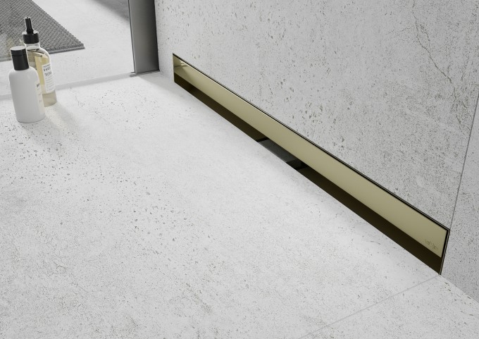Golden linear drain in a concrete bathroom